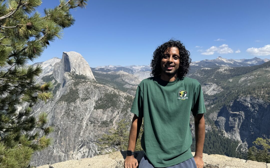 Image of a person standing leaning on a wall in front of a mountain at Yosemite.